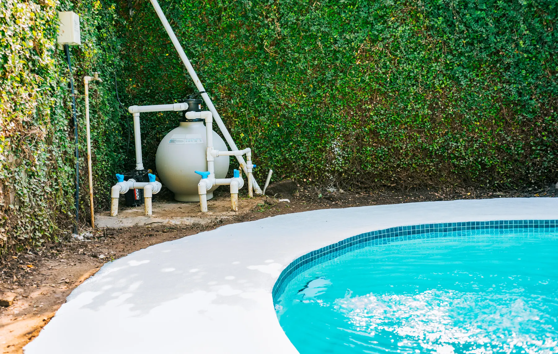 A residential pool pump and sand filter system installed poolside, illustrating the kind of equipment repair and equipment work covers
